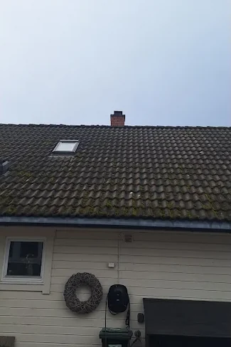 Tak med mørke betongtakstein, dekket av mose og grønske